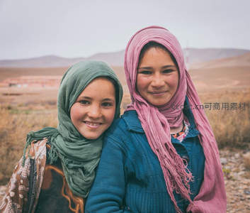 沙漠边缘两位戴头巾女孩的纯真笑容