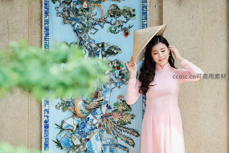 粉裙女子戴斗笠倚墙浅笑