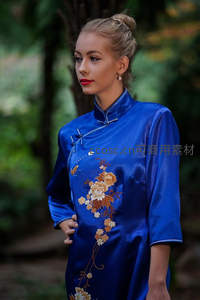 蓝缎旗袍女子林间静立花影相伴