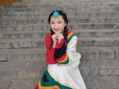 彩衣藏族少女笑坐石阶上
