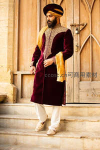 印度男子身着酒红色礼服立于古建筑前