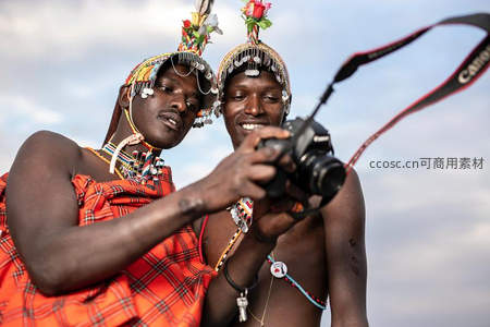 两位身着部落服饰的男子专注操作相机