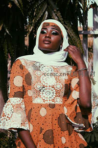 头戴白色头巾的非洲女性在绿植前优雅凝视