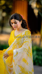 黄白扎染纱丽女子低头凝思于柔光庭院中