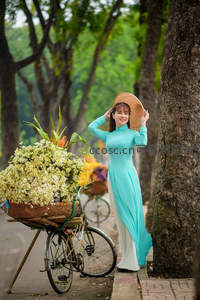 绿荫小径上身着奥黛的花贩女子