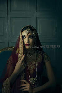华丽传统服饰女子端坐深色背景前