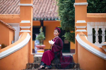 橙墙拱门下红裙女子持莲