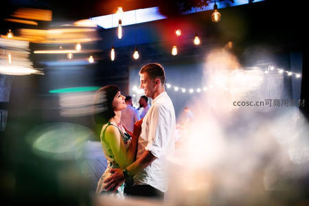 灯光闪烁下深情相拥的舞动情侣