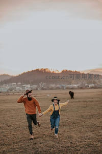 情侣在黄昏草地上奔跑欢笑