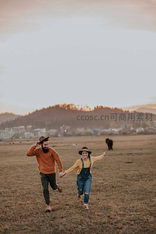 情侣在黄昏草地上奔跑欢笑