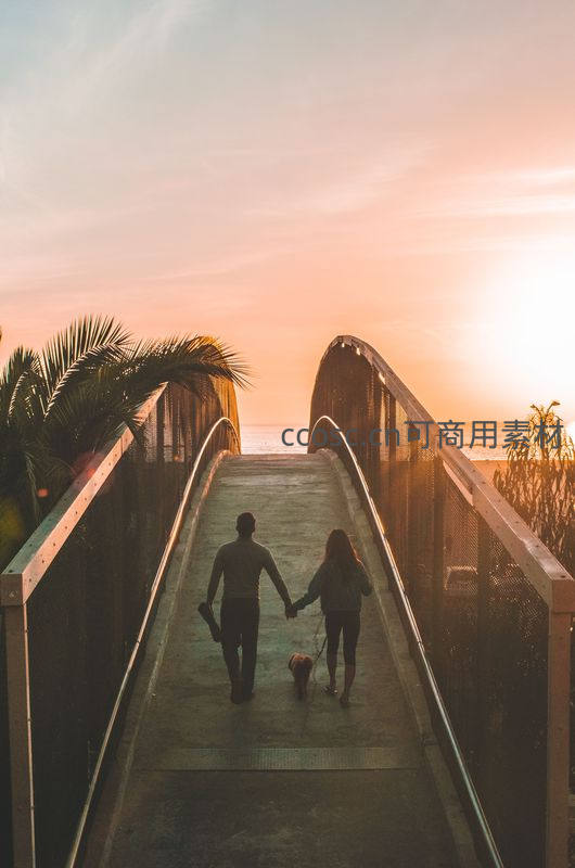 夕阳下情侣牵手漫步海边栈桥