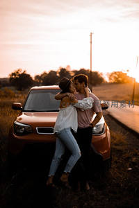 夕阳公路旁情侣车前相拥