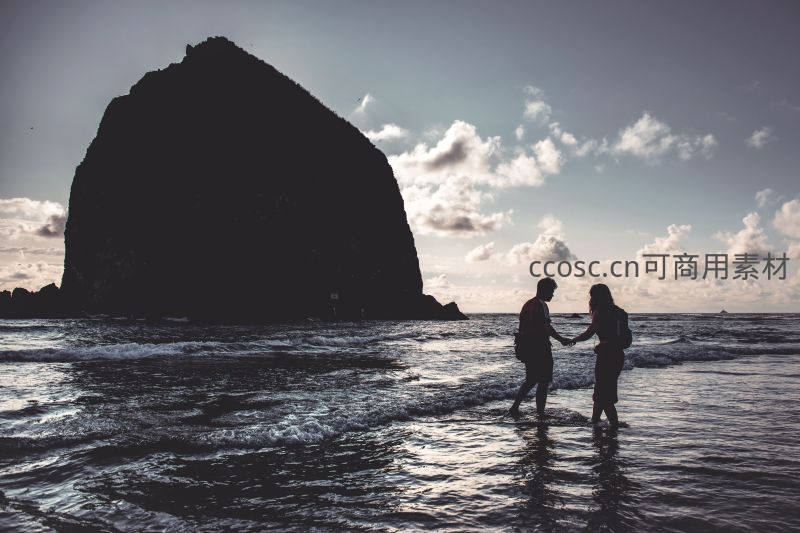 海岸剪影情侣牵手漫步潮汐