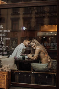 咖啡馆窗内情侣依偎谈笑