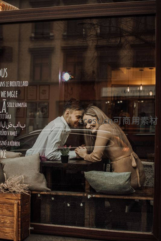 咖啡馆窗内情侣依偎谈笑