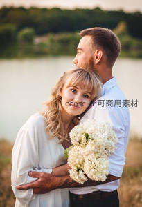 湖畔情侣怀抱鲜花甜蜜依偎