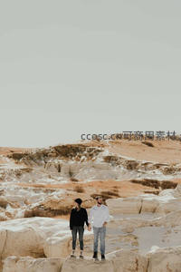 情侣手牵手漫步在荒漠岩层之上