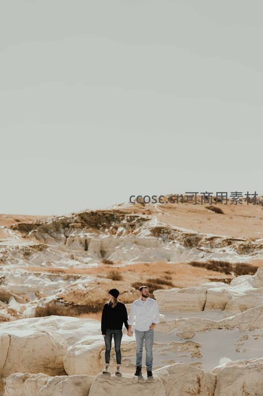 情侣手牵手漫步在荒漠岩层之上