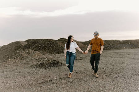 情侣牵手走在砾石荒地上享受黄昏