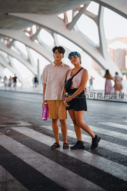 现代桥梁下年轻情侣携手漫步街头