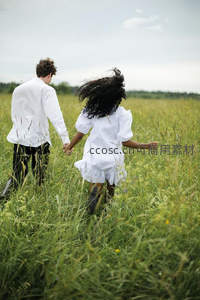 情侣手牵手奔跑在青翠草地上
