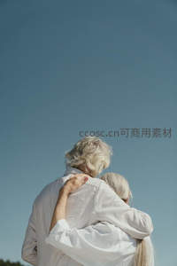 白发老人相拥仰望蔚蓝天空