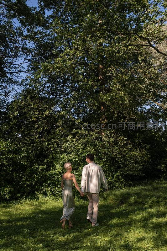 林间牵手漫步的恋人背影