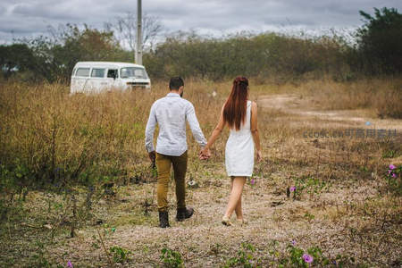 情侣牵手漫步荒野小径，复古面包车静候远方