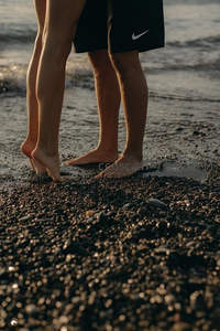 情侣赤脚踩在海滩石子上