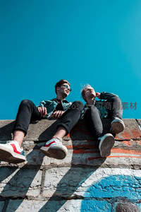 蓝天下的年轻情侣坐在涂鸦墙边