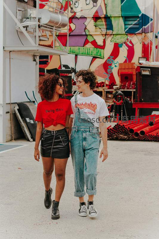 街头涂鸦墙前漫步的时尚情侣