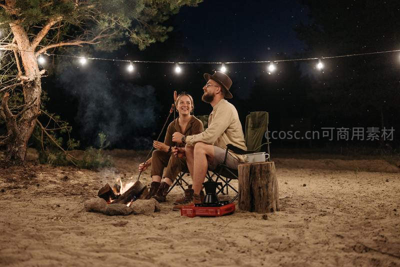 星空下情侣围坐篝火享受露营夜晚