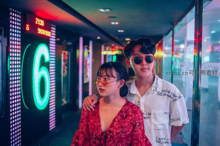 霓虹走廊中时尚情侣漫步影院通道