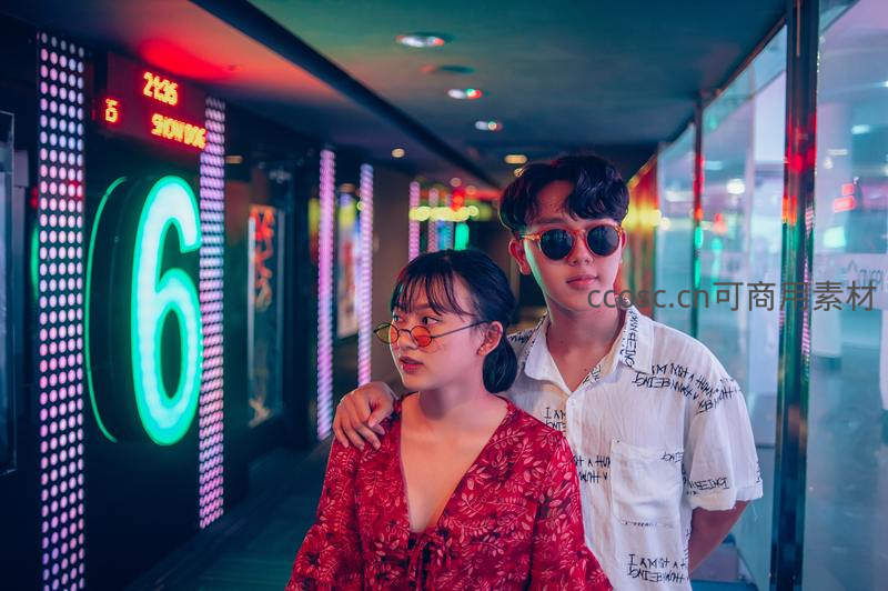 霓虹走廊中时尚情侣漫步影院通道