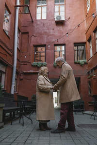 红墙庭院里，老夫妇相视而笑牵手漫步