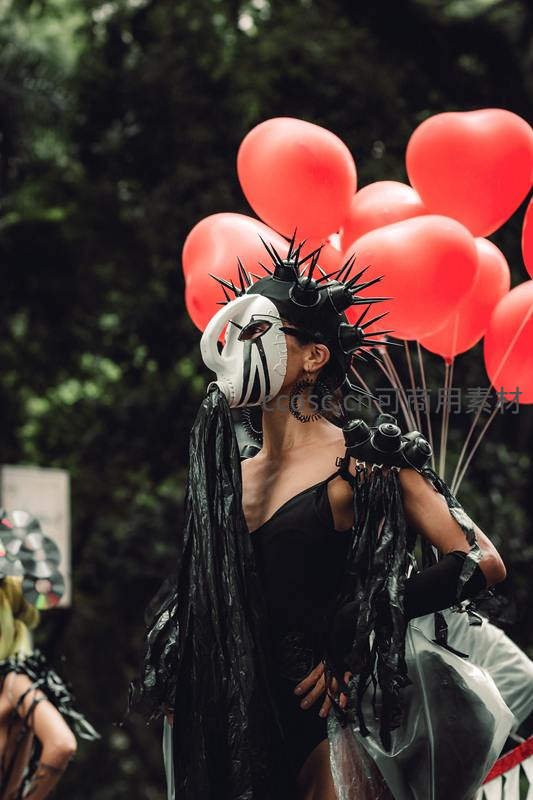 面具舞者手持红气球街头表演
