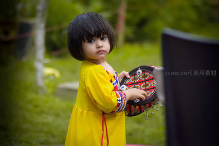 黄裙小女孩手持民族风手鼓回眸