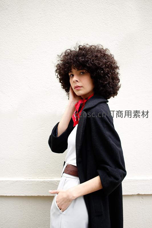 卷发女子靠墙沉思，红巾点缀时尚造型