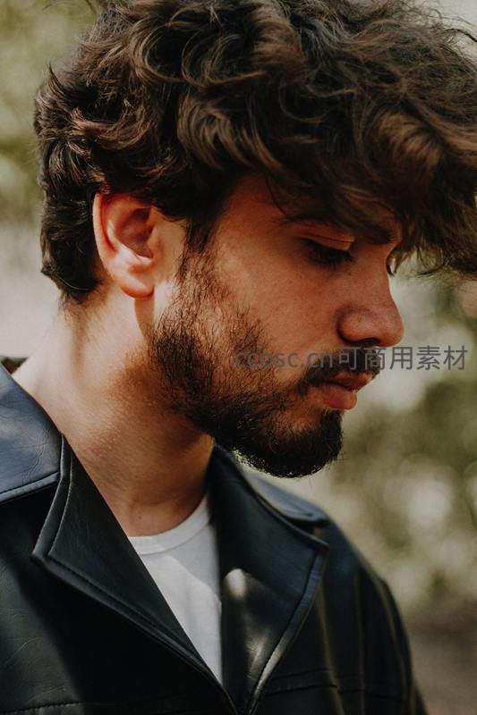 卷发胡须男子侧脸特写，皮衣质感尽显帅气