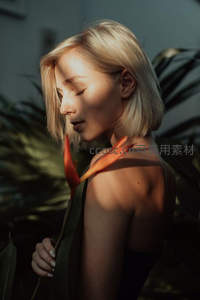 金发女子侧颜凝视，热带植物映衬下的温柔光影