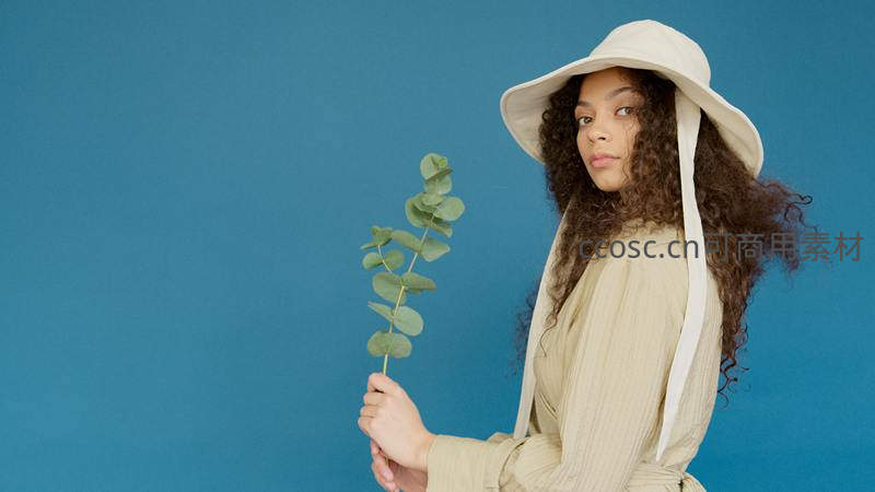 卷发女子戴帽持桉树叶凝视
