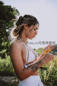 阳光下手持野花的度假女子