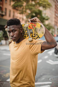 城市街头肩扛滑板的青年