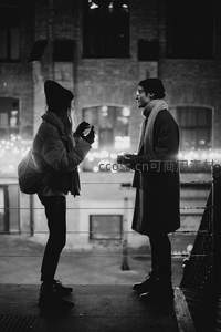 冬夜桥上情侣对望分享热饮温馨时刻