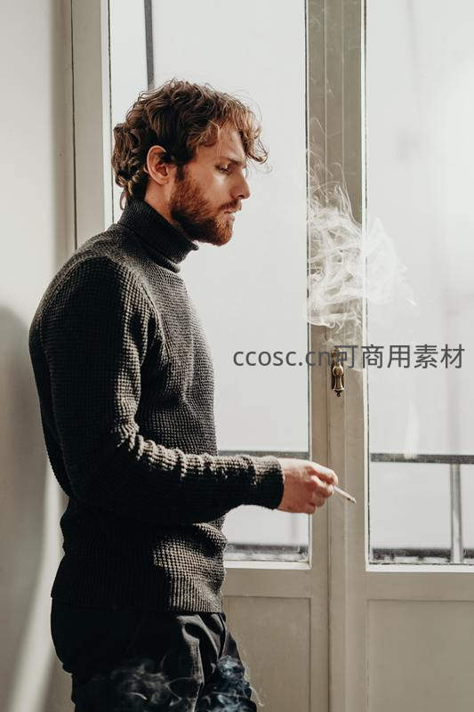 卷发男子窗边沉思抽烟