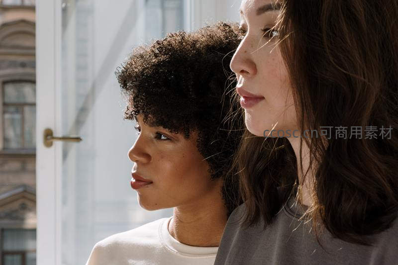 两位女性并肩凝望窗外城市风景