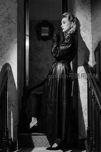 黑裙女子倚靠楼梯回眸演绎复古风情