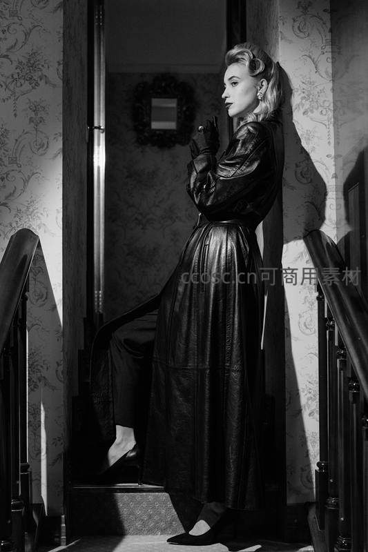 黑裙女子倚靠楼梯回眸演绎复古风情