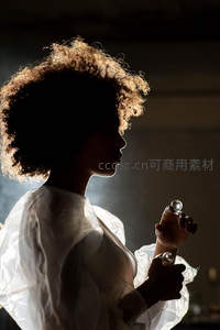 逆光下卷发女子手持水晶球剪影