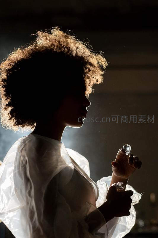 逆光下卷发女子手持水晶球剪影
